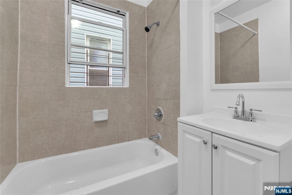 54 3rd Street, Unit 3 Newark, NJ 07107 - Photo 13 of 15 a bathroom with a granite countertop sink mirror and a bathtub