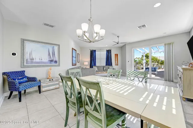 a view of a dining room with furniture a chandelier and kitchen view