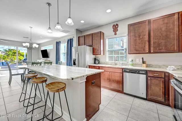 a kitchen with stainless steel appliances granite countertop a stove top oven a sink dishwasher and a refrigerator with wooden cabinets