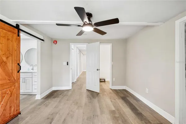 a view of empty room with wooden floor and fan