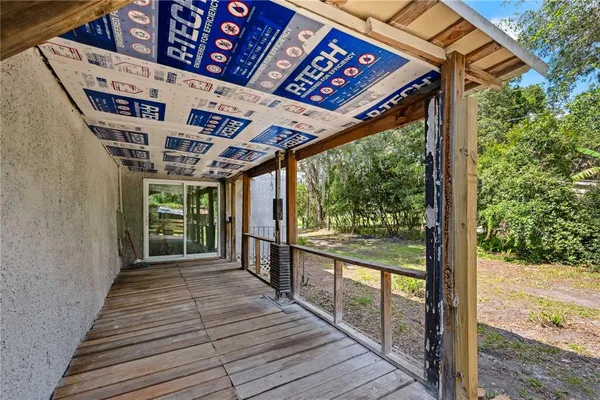 a porch with wooden floor next to a yard