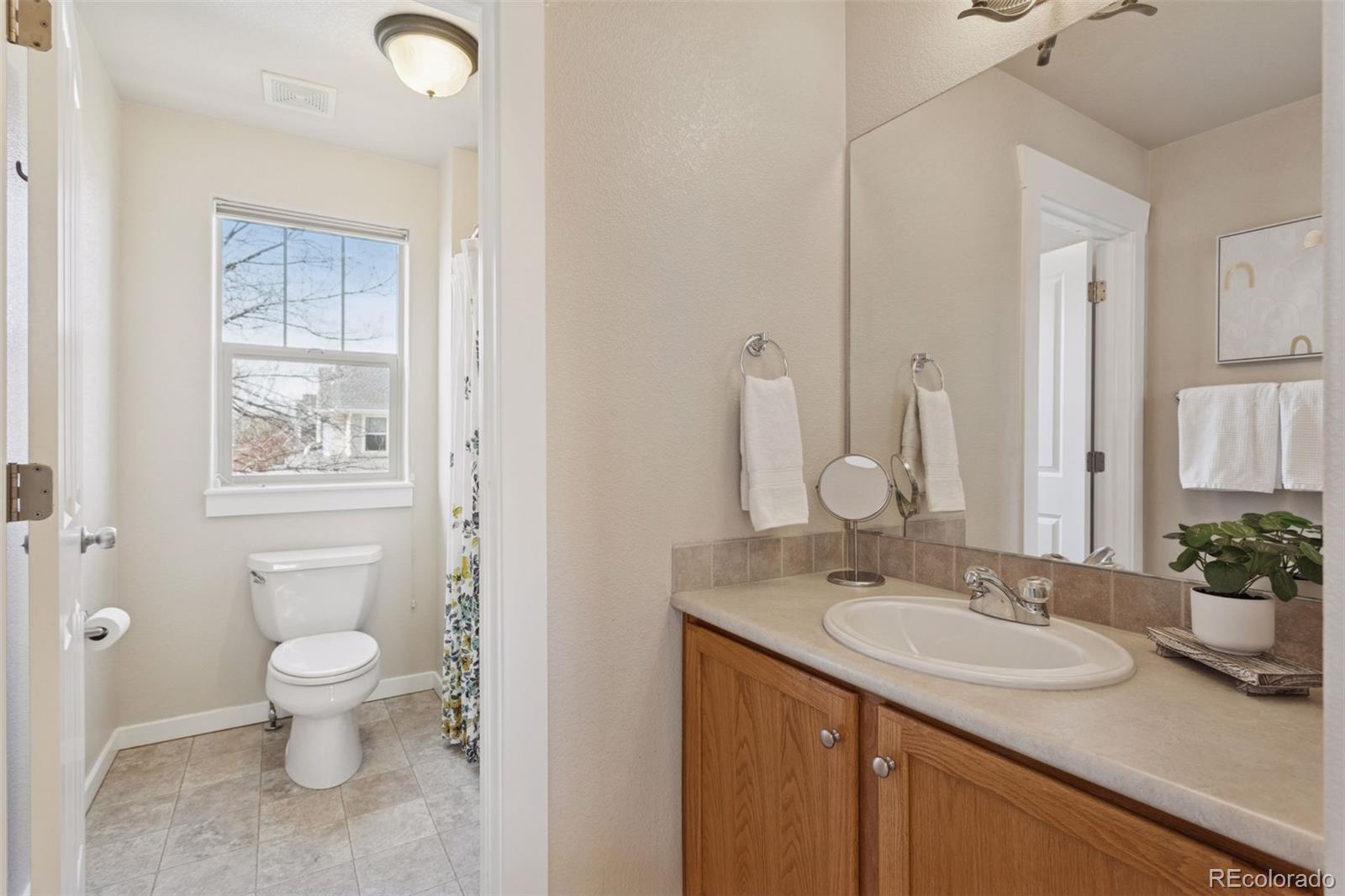 2882 Alton Street Denver, CO 80238 - Photo 22 of 42 a bathroom with a granite countertop sink a toilet and a mirror