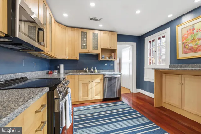 a kitchen with stainless steel appliances granite countertop a refrigerator a sink dishwasher and wooden cabinets with wooden floor