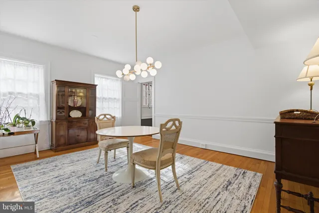 a dining room with chandelier and wooden floor
