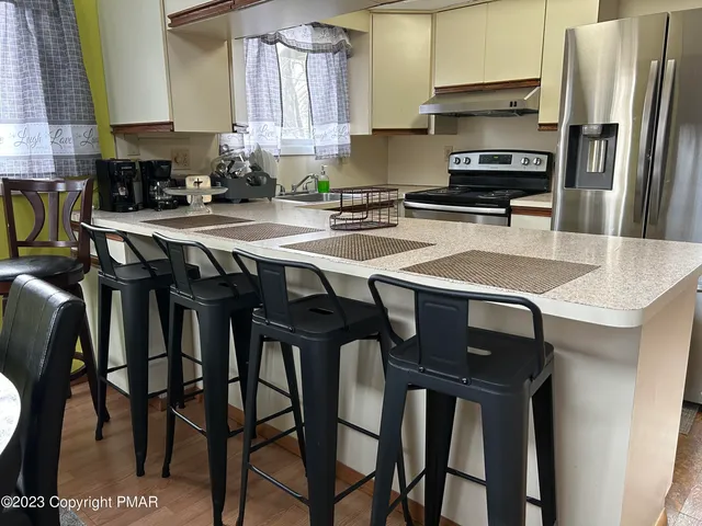a kitchen with stainless steel appliances granite countertop a table chairs microwave and sink