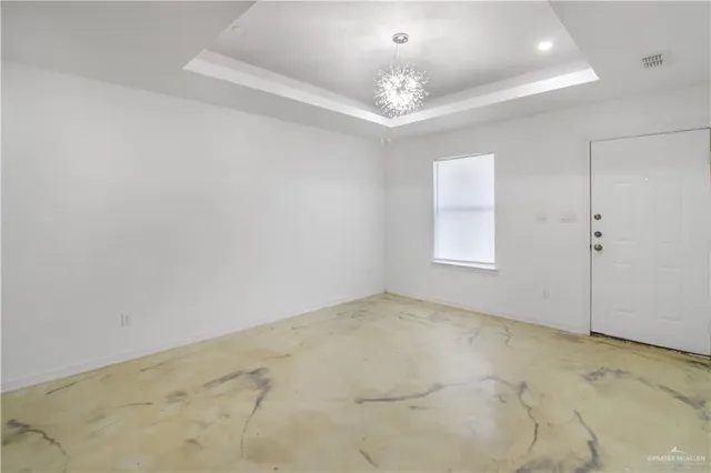 an empty room with a chandelier fan and windows