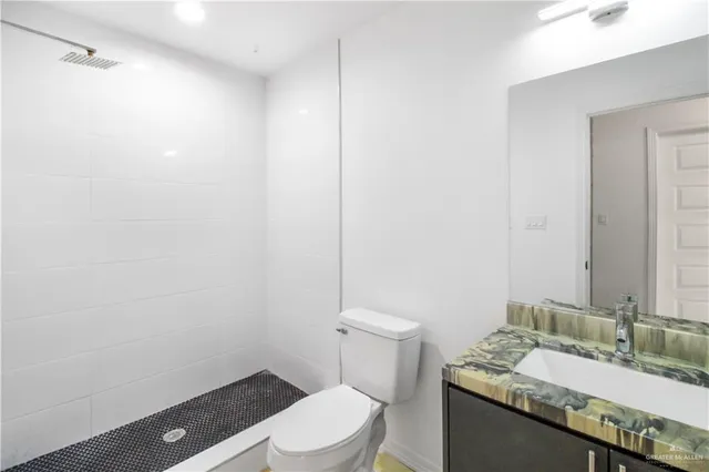 a bathroom with a granite countertop sink mirror vanity and toilet