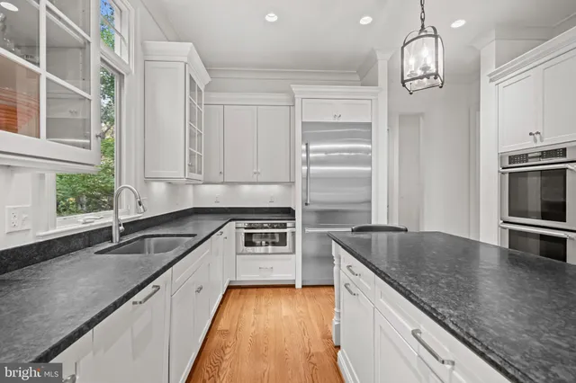 a kitchen with stainless steel appliances granite countertop a sink a stove a refrigerator and cabinets