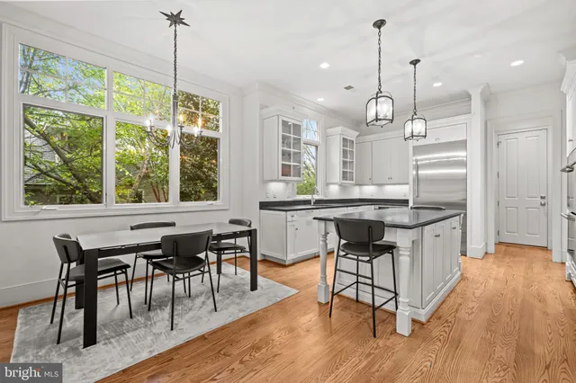 a kitchen with kitchen island granite countertop a table chairs a sink dishwasher window and wooden floor