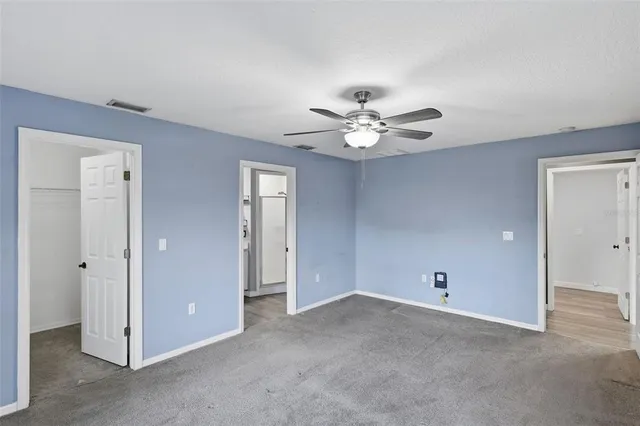 an empty room with a fan & a window