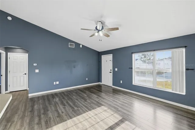 a view of an empty room with a window and wooden floor