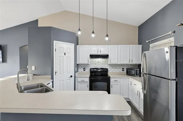 a kitchen with stainless steel appliances a refrigerator sink and white cabinets