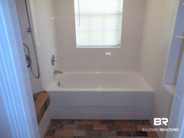 28202 Vargo Lane Elberta, AL 36530 - Photo 23 of 45 This tub/shower is in the bedroom on the West end of the home. Ceramic tile walls. Brick floor. Bench. Shelving.