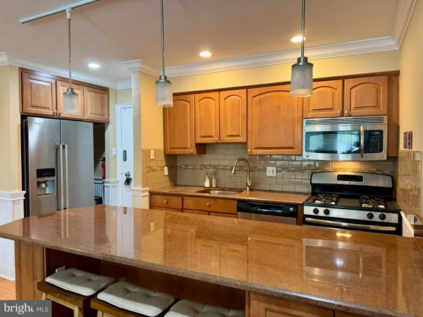 a kitchen with stainless steel appliances a sink a stove a refrigerator cabinets and wooden floor