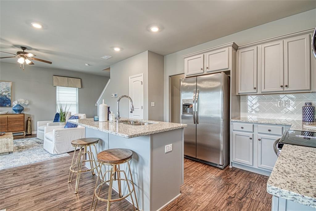 11951 Brightside Parkway Hampton, GA 30228 - Photo 11 of 25 a kitchen with stainless steel appliances granite countertop a refrigerator a sink dishwasher a dining table and chairs with wooden floor