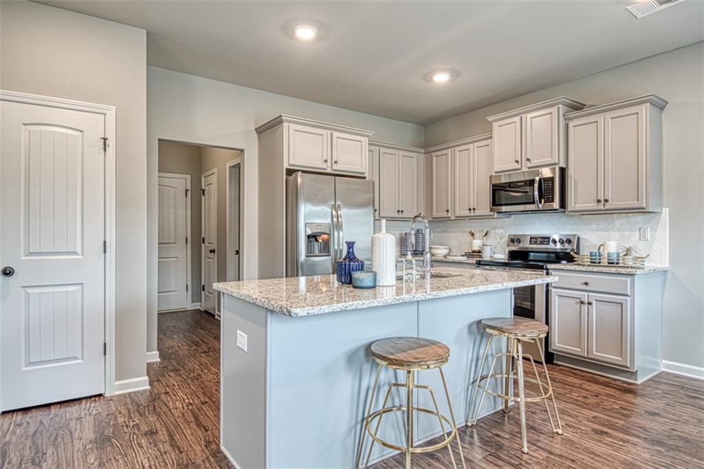 11951 Brightside Parkway Hampton, GA 30228 - Photo 10 of 25 a kitchen with stainless steel appliances granite countertop a stove top oven a sink dishwasher and a refrigerator with wooden floor