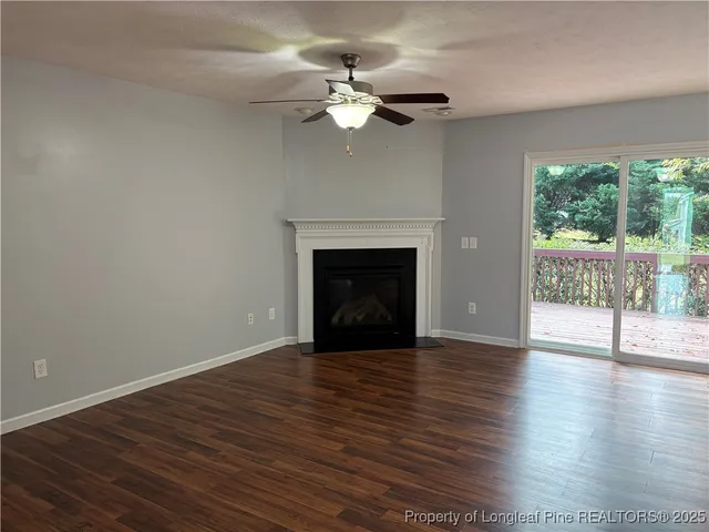 a view of an empty room with wooden floor and a fireplace