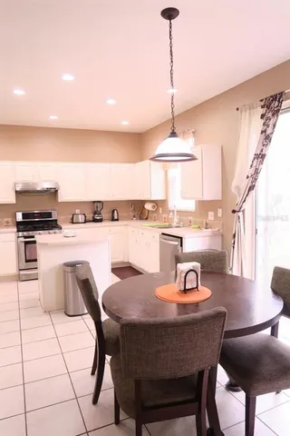 a outdoor kitchen with stainless steel appliances kitchen island granite countertop a sink a stove a dining table and chairs