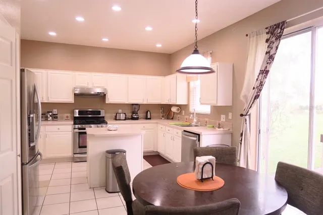 a kitchen with stainless steel appliances kitchen island granite countertop a sink and a refrigerator