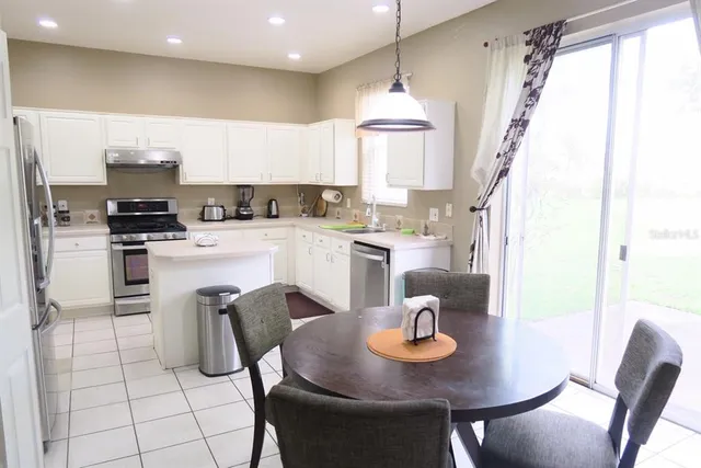 a kitchen with stainless steel appliances granite countertop a sink a stove a kitchen island with chairs and white cabinets