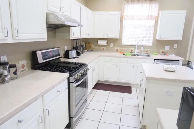a kitchen with cabinets appliances a sink and a window