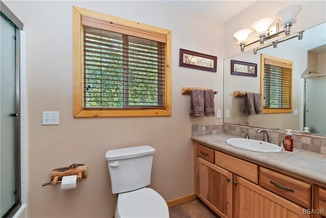 a bathroom with a toilet a sink a mirror and a window