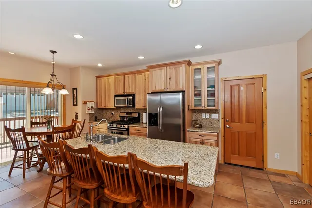 a kitchen with stainless steel appliances granite countertop a dining table chairs refrigerator and cabinets
