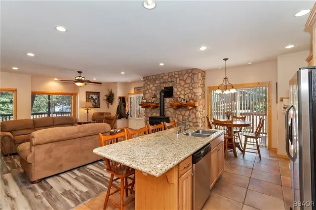 a living room with stainless steel appliances furniture a rug and a kitchen view