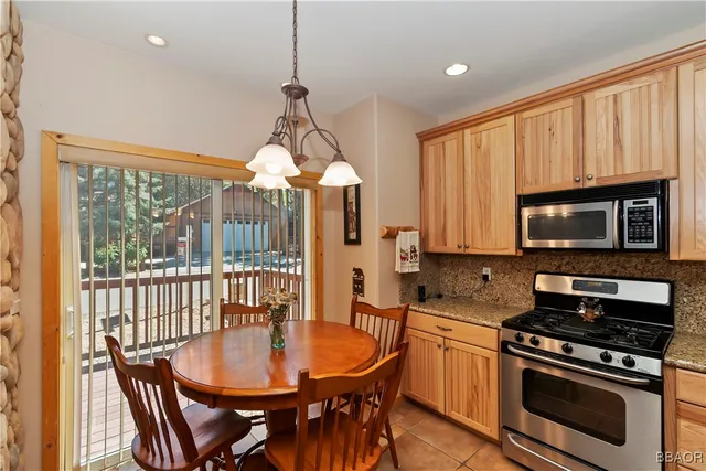 a kitchen with stainless steel appliances granite countertop a stove a sink a microwave a dining table and chairs