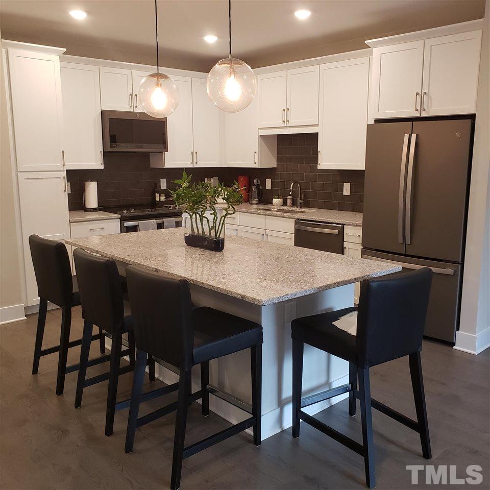 105 Chatham Walk Lane, Unit 404 Cary, NC 27511 - Photo 4 of 12 a kitchen with stainless steel appliances granite countertop a stove a refrigerator a kitchen island a dining table and chairs