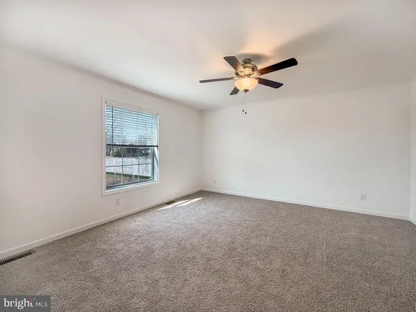 an empty room with a window and a fan