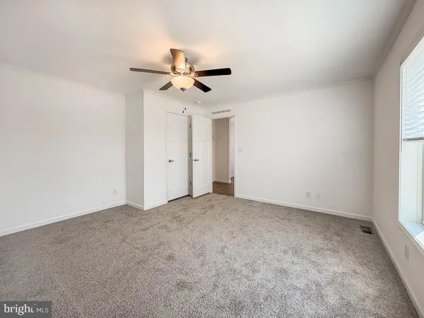 an empty room with a window and a fan