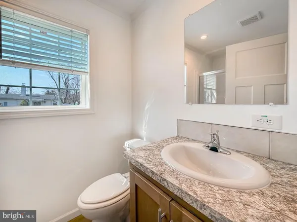 a bathroom with a granite countertop sink a toilet and a mirror