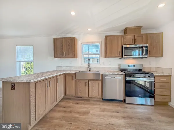 a kitchen with stainless steel appliances a stove a sink a microwave a refrigerator and cabinets
