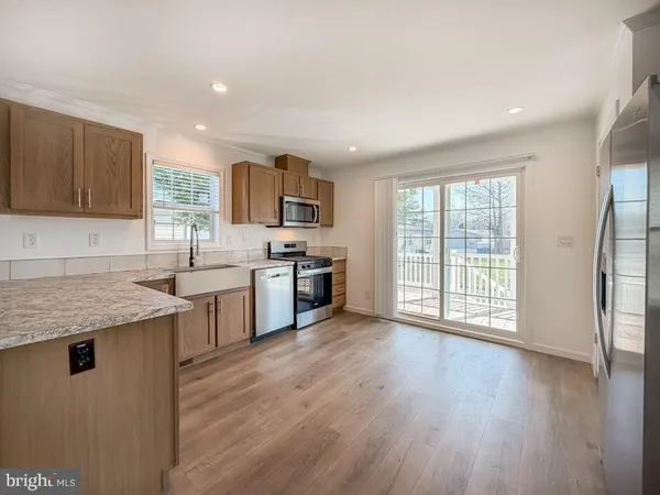 a kitchen with stainless steel appliances granite countertop a stove a sink dishwasher a refrigerator and a microwave oven with wooden floor