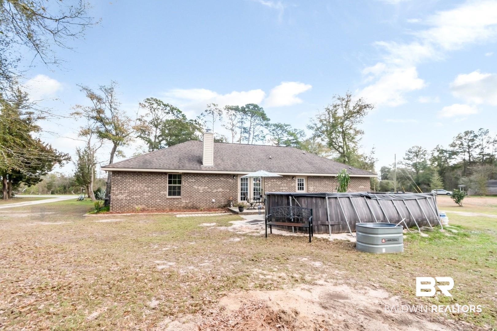 11528 Mocking Bird Lane Fairhope, AL 36532 - Photo 32 of 45 Rear view of property with a covered pool, a chimney, brick siding, and a yard