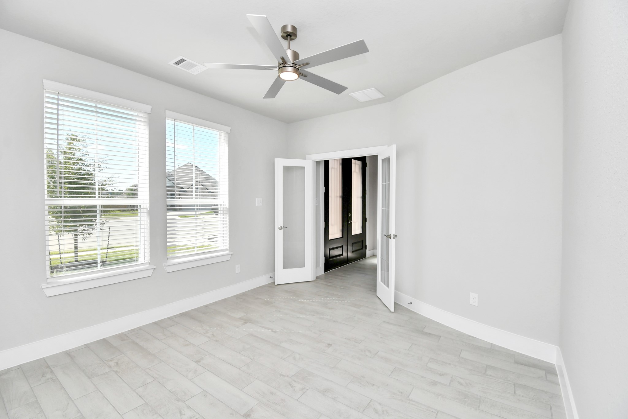 3106 Native Spg Drive Spring, TX 77373 - Photo 6 of 38 Experience the perfect blend of sophistication and warmth in this home office, boasting elegant wood-look tile flooring and flooded with natural light from expansive windows and French doors. Sample photo of completed home with similar floor plan. Actual colors and selections may vary.