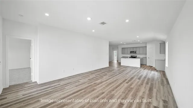a view of kitchen and empty room with wooden floor