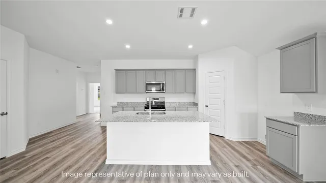 a large white kitchen with kitchen island a sink stainless steel appliances and white cabinets