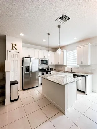 a kitchen with stainless steel appliances kitchen island granite countertop a refrigerator a stove a sink and a refrigerator