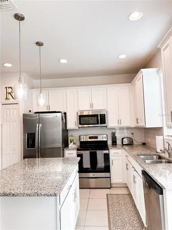 a kitchen with stainless steel appliances granite countertop a sink a stove a refrigerator and cabinets