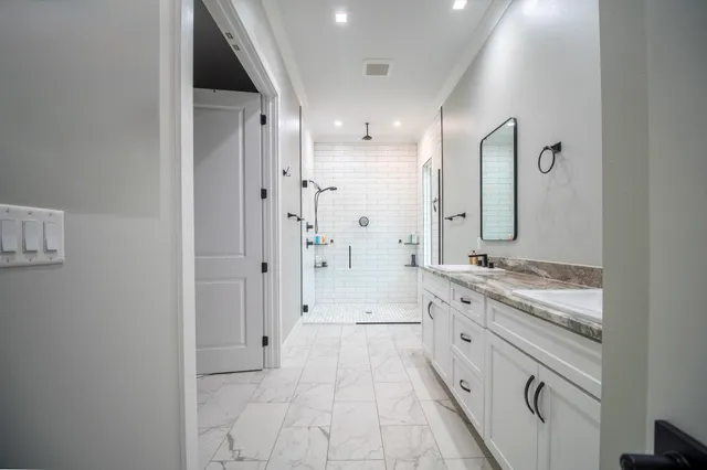 a bathroom with a granite countertop sink a large mirror and a shower
