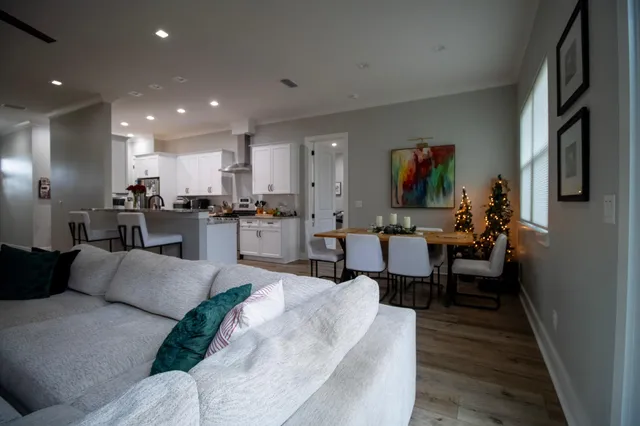 a living room with furniture kitchen view and a wooden floor