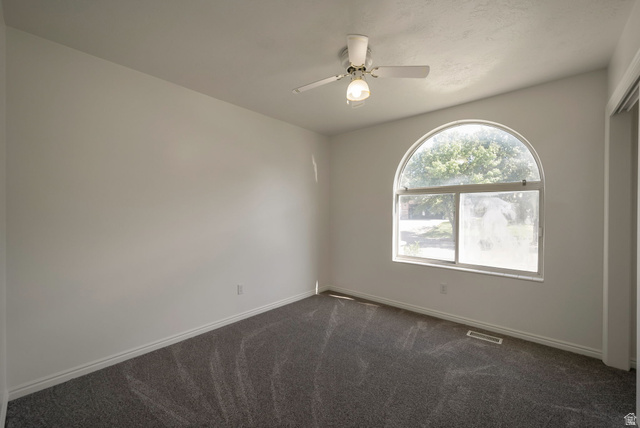11922 Bluff View Drive Sandy, UT 84092 - Photo 11 of 30 Empty room with dark carpet and ceiling fan