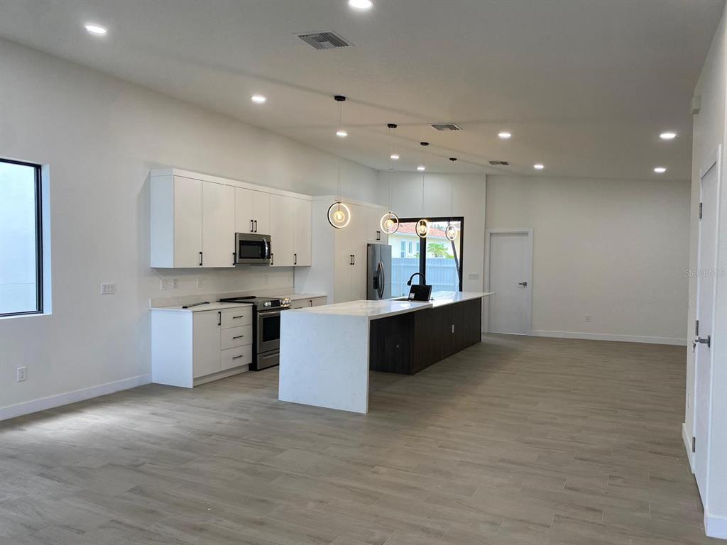 a large white kitchen with a large counter top and stainless steel appliances
