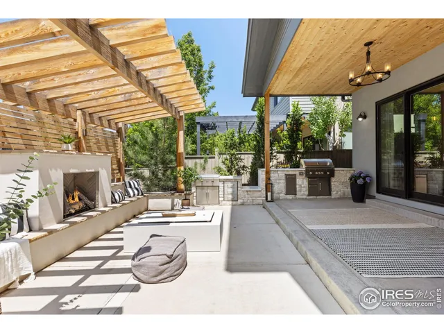 a view of a patio with couches and table and chairs under an umbrella with a fireplace