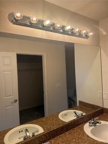 a bathroom with a granite countertop sink a toilet a mirror and vanity