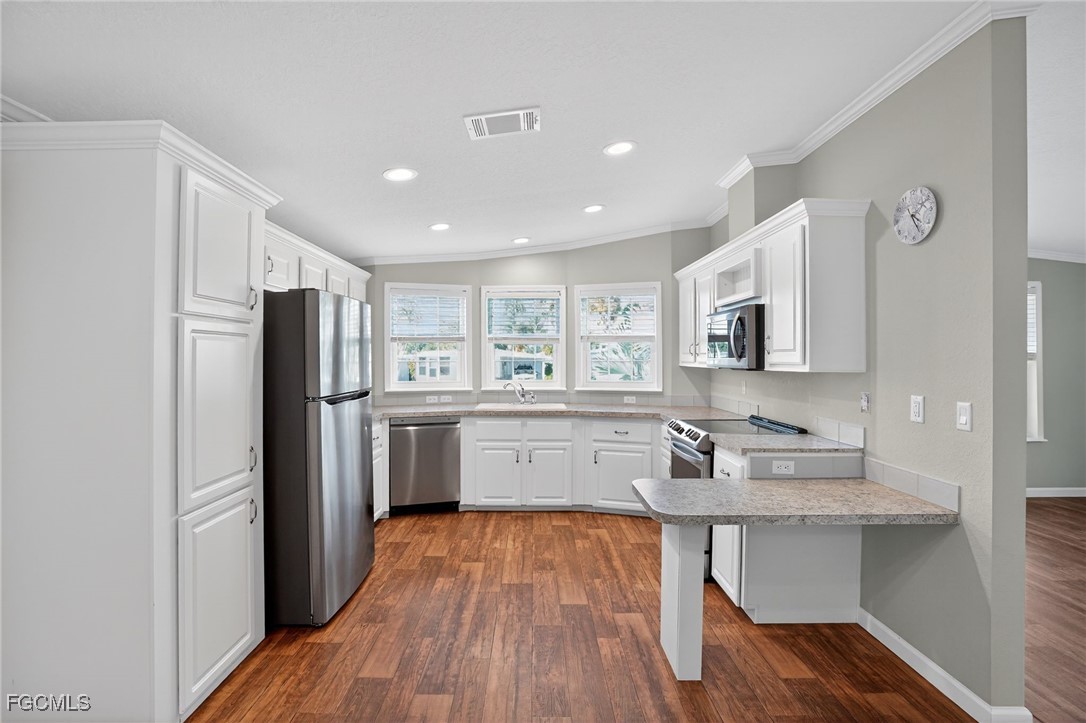 516 Menton Lane Naples, FL 34112 - Photo 14 of 34 a kitchen with white cabinets and stainless steel appliances
