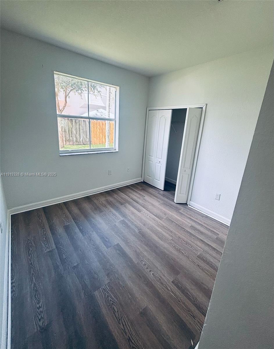 1663 Southeast 29th Street, Unit 100 Homestead, FL 33035 - Photo 13 of 15 an empty room with wooden floor and windows