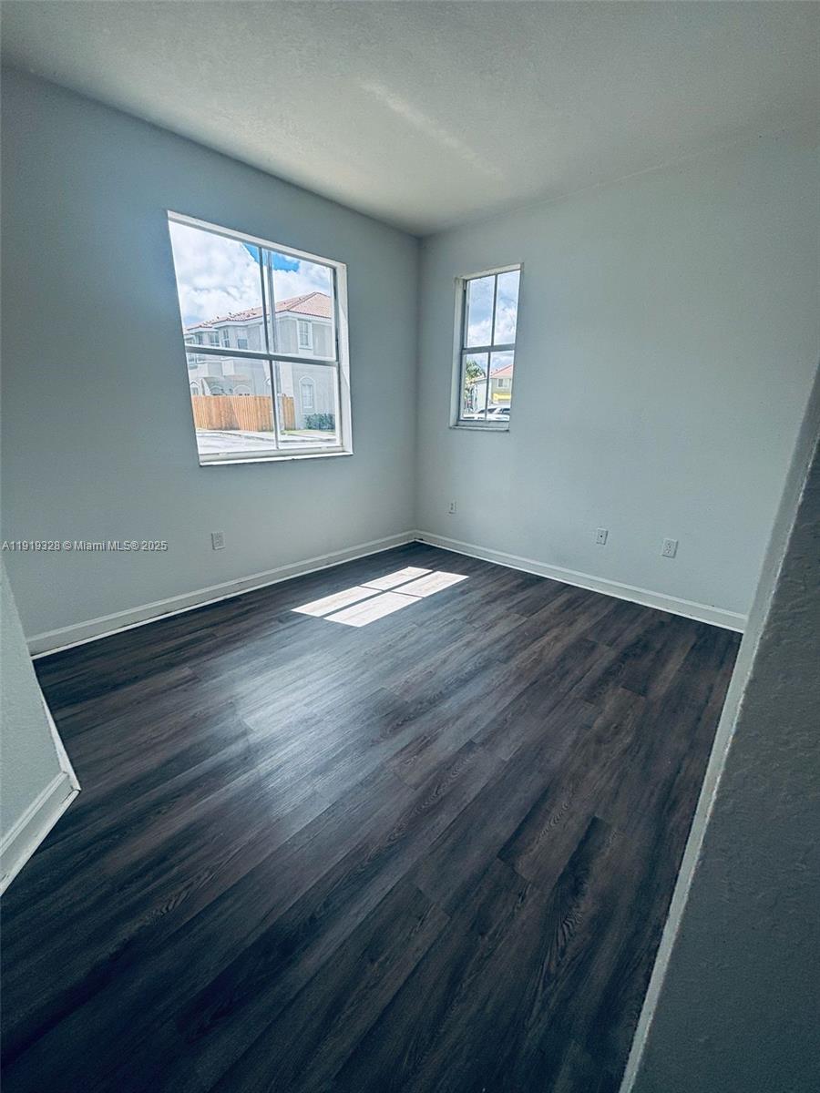 1663 Southeast 29th Street, Unit 100 Homestead, FL 33035 - Photo 7 of 15 a view of an empty room with wooden floor and a window